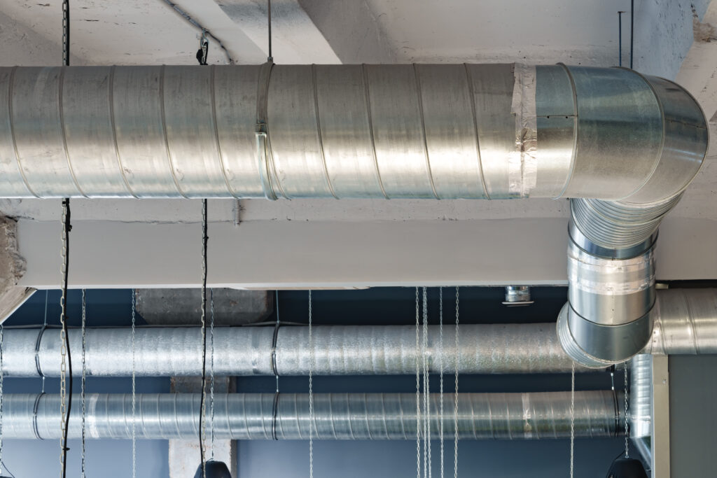 Silver ventilation pipes hanging from the ceiling inside the building close up